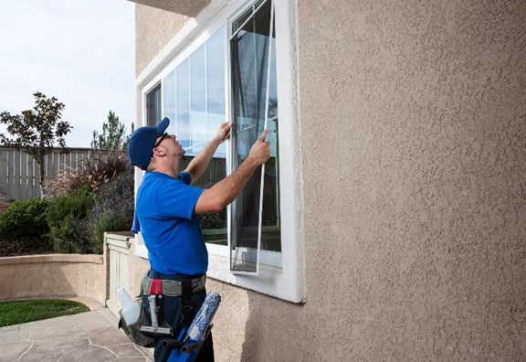 A man removes a window screen for cleaning