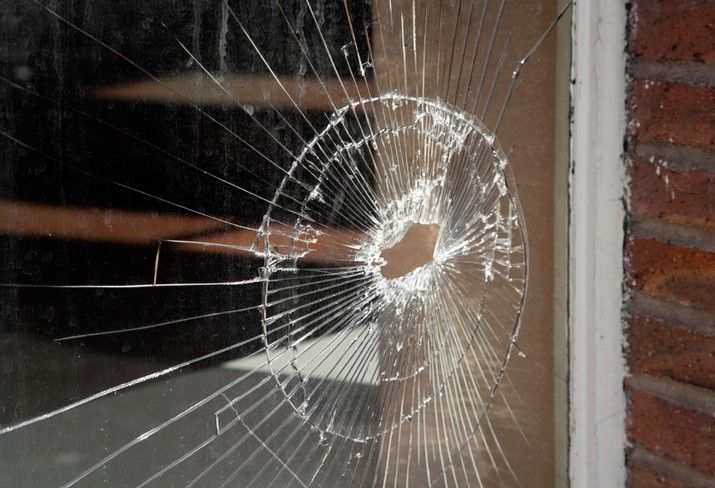 Double-pane window in Maryland showing a bullet hole and broken glass