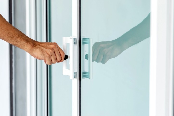 A person in Pennsylvania opens a glass door, ensuring it is clean and lubricated