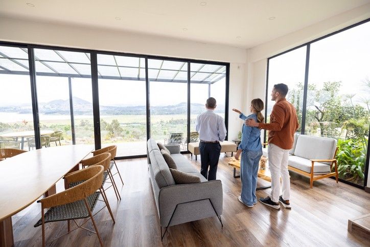 Three individuals in a spacious living room with large windows, set in Maryland